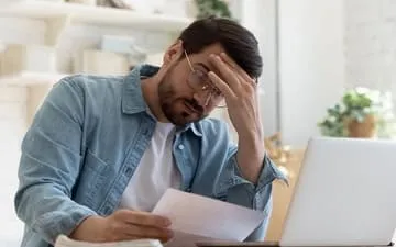 O que são danos materiais? Na imagem, dono de empresa preocupado em seu escritório porque não contratou o seguro patrimonial empresarial.