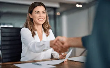 Dona de uma empresa apertando mão de locador após apresentar a apólice do seguro fiança aluguel