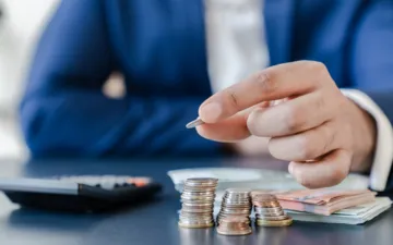 O que é o seguro crédito? Na imagem, dono de empresa contando moedas em alusão à importância desse seguro contra a inadimplência de clientes em compras a prazo.