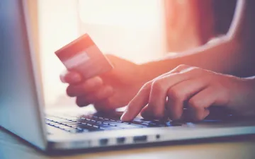 Como funciona o seguro de crédito? Na imagem, dono de empresa segurando cartão de crédito em alusão à importância desse seguro contra a inadimplência de clientes em compras a prazo.