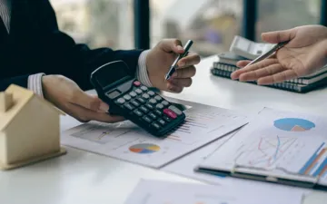 O que é o seguro de crédito para PME? Na imagem, empresa fazendo cálculos para entender todos os benefícios desse seguro contra inadimplência de clientes.