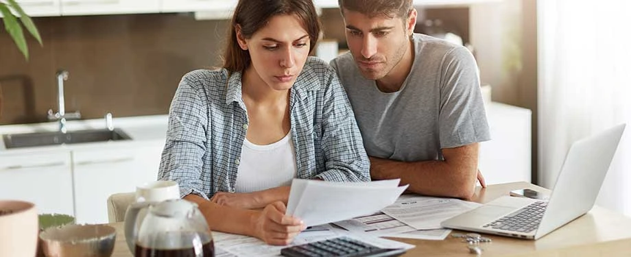 Qual o valor do seguro fiança para um imóvel alugado? Na imagem, casal analisa proposta de seguro fiança aluguel, cujo valor depende de diversos fatores, como  coberturas e histórico do locatário 