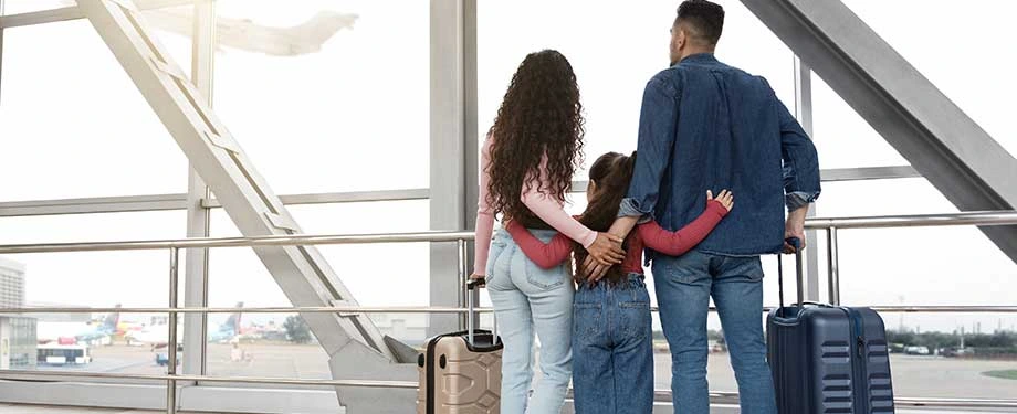Qual é a seguradora mais confiável para contratar seguro para viagem? Na imagem, família se abraça em aeroporto em alusão à proteção do seguro de viagem, que deve ser contratado com uma seguradora de confiança