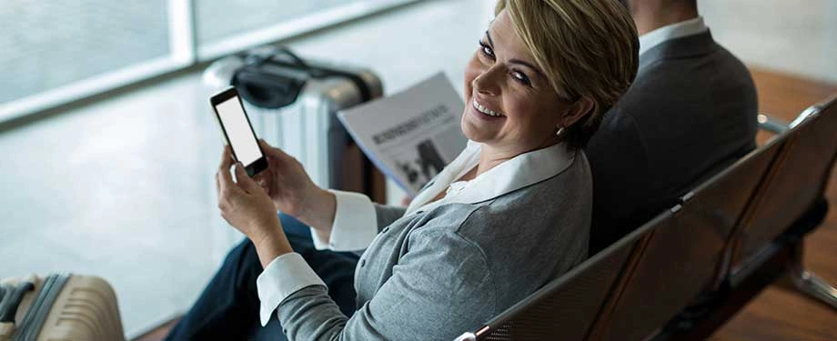 Quanto custa um Assist Card? Na imagem, mulher utiliza celular para contratar seguro viagem Assist Card