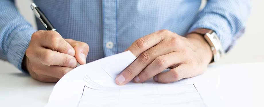Como contratar? Na imagem, pessoa assinando apólice de seguro garantia contratual após entrar em contato com corretora de seguros digital
