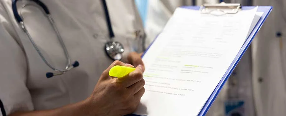 Como contratar o seguro hospital? Na imagem, m&eacute;dico com prontu&aacute;rio de paciente refor&ccedil;a a import&acirc;ncia de institui&ccedil;&otilde;es de sa&uacute;de contratarem o seguro hospital 