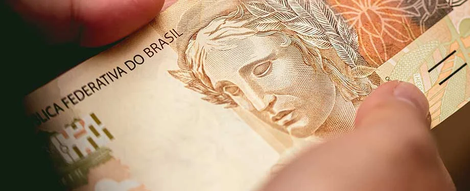 Homem segurando uma nota de cinquenta reais ilustrando a ideia de seguro prestamista empresarial