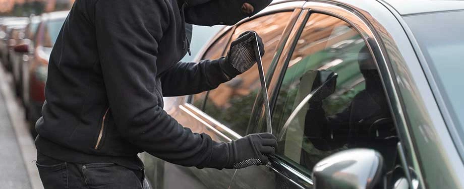 Quanto custa um seguro contra roubo de carro? Na imagem, homem roubando carro em alus&atilde;o ao seguro auto, cujo valor depende de fatores como modelo do ve&iacute;culo, coberturas contratadas e seguradora escolhida 