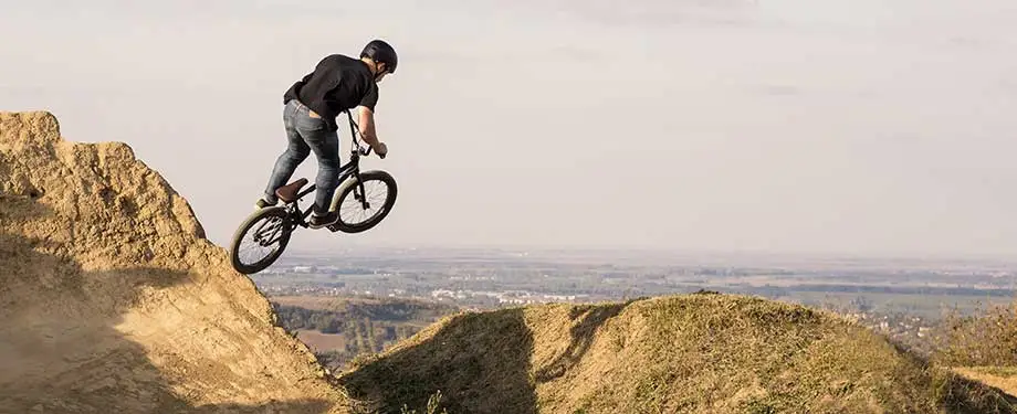 Como contratar seguro viagem para esportes radicais? Na imagem, pessoa andando de bike representa modalidade de seguro viagem que pode ser contratada com orienta&ccedil;&atilde;o de corretora de seguros 