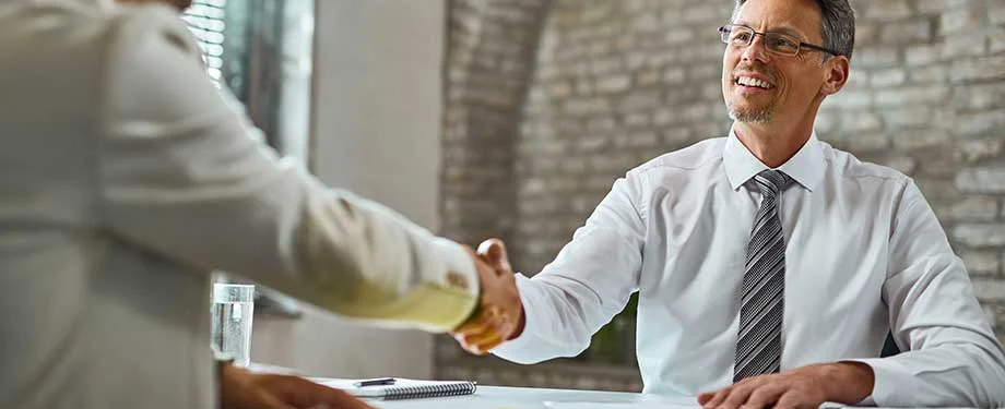 Qual o valor de um seguro para empresa? Na imagem, empreendedores apertam a mão representando acordo protegido por seguro garantia para empresas