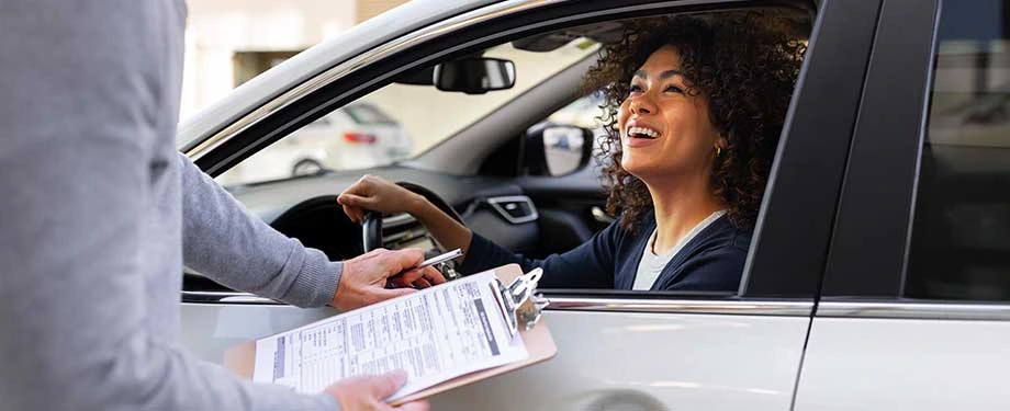 Qual o valor de um seguro automóvel? Na imagem, mulher conversa com corretor para contratar seguro automóvel e proteger seu veículo