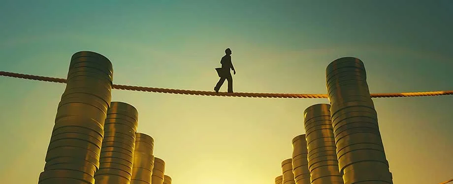 Como funciona o stop loss? Na imagem, pessoa atravessando corda bamba em alus&atilde;o ao seguro stop loss, cujo excesso de sinistralidade fica a cargo da resseguradora 