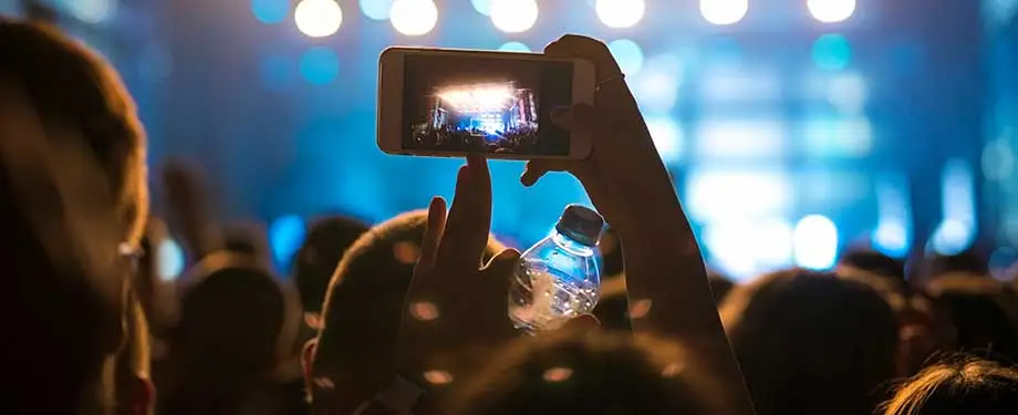 O que cobre o seguro RC eventos? Na imagem, pessoa gravando show com celular representa a importância do RC eventos, que garante cobertura aos organizadores em caso de danos a terceiros