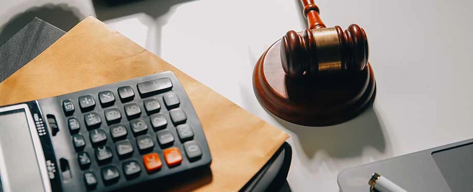Como funciona o seguro garantia judicial? Na imagem, martelo da justiça e calculadora representam que seguro garantia pode ser usado como garantias em processos de execução fiscal