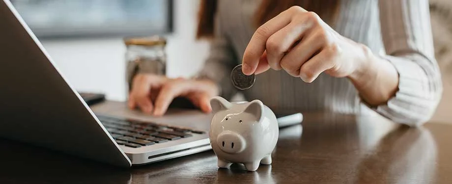 O que quer dizer seguro renda protegida? Na imagem, mulher colocando moeda em cofre representa seguro renda protegida, que garante indeniza&ccedil;&atilde;o em caso de incapacidade de trabalhar 