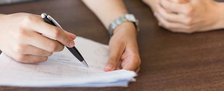 Onde consigo contrato social? Na imagem, pessoa segura caneta e lê contrato, que não pode ser acessado de forma digital
