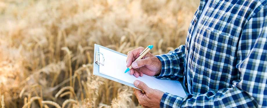 Quem tem direito ao plano Safra? Na imagem, agricultor com prancheta representa a importância do seguro safra para proteção contra eventos climáticos