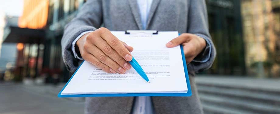 O que cobre um seguro garantia? Na imagem, homem com prancheta e caneta para assinatura de contrato de seguro garantia manutenção