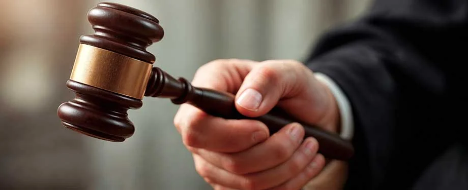 Como funciona o seguro garantia leiloeiro? Na imagem, pessoa segurando martelo da justiça representa o seguro garantia leiloeiro, importante para assegurar o cumprimento contratual