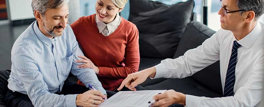 O que é melhor: fiador ou seguro fiança? Na imagem, casal sorridente assina apólice após decidir que seguro fiança aluguel era a opção mais vantajosa 