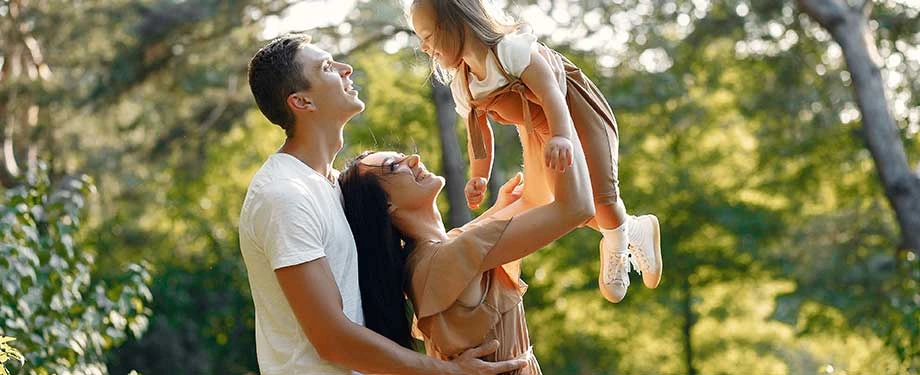 Para que serve um seguro de vida de 500 mil? Na imagem, casal brinca com filha representando a importância de garantir a segurança por meio de uma apólice de vida