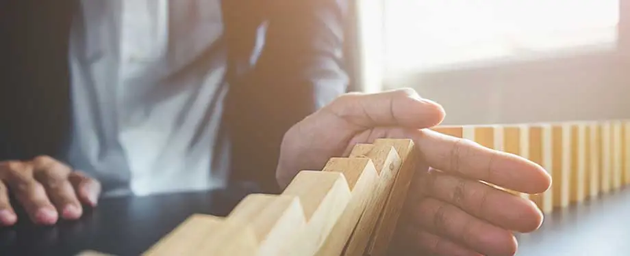 Para quem o seguro de riscos diversos é indicado? Na imagem, mãos seguram peças de madeiram caindo, evidenciando que o seguro pode ser contratado por pessoas físicas ou jurídicas para proteger seu patrimônio