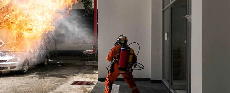 Quanto custa um seguro contra incêndio comercial? Na imagem, profissional tenta conter fogo após acidente, evidenciando a importância da cobertura de um seguro para lidar com os prejuízos