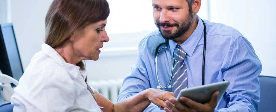 Quais doenças o seguro cobre? Na imagem, médico conversando com paciente representa a possibilidade de proteção em caso de doenças graves como câncer e AVC