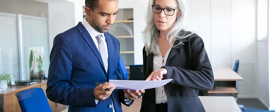 Como funciona o seguro de empresa? Na imagem, vemos contratante e prestador de serviços conferindo apólice de seguro garantia para empresas