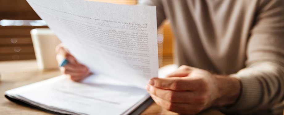 O que é seguro garantia manutenção corretiva? Na imagem, homem lê apólice de seguro que protege contra problemas com má qualidade do produto
