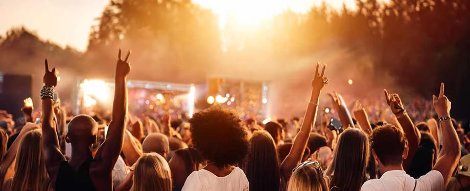 V&aacute;rias pessoas aproveitando uma festa ao ar livre durante o p&ocirc;r do sol ilustrando a ideia de um seguro festa