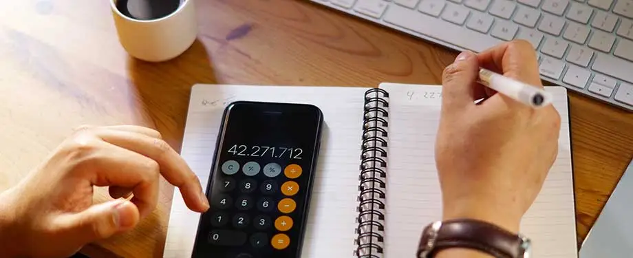 O que é marco legal das garantias? Na imagem, homem utiliza celular e caderno para fazer cálculos em representação a redução das taxas de juros possibilitada pelo marco legal de garantias