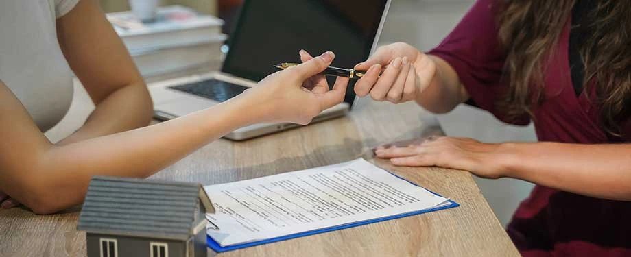 Quais são as desvantagens do seguro fiança? Na imagem, inquilino pega caneta para contratar o seguro locação, que deixa o aluguel mais caro, mas garante o cumprimento do contrato