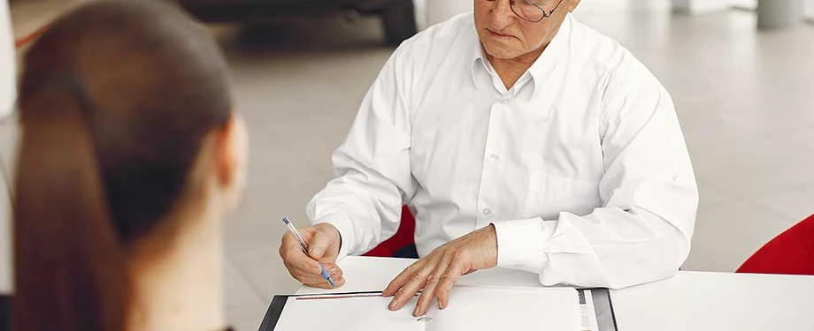 Qual a diferença entre tomador e segurado em um seguro garantia? Na imagem, homem assinando contrato representa que o tomador contrata o seguro e o segurado é protegido pela apólice