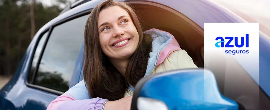 Qual a diferença entre a Azul e a Porto Seguro? Na imagem, mulher na janela de carro sorri evidenciando as vantagens de contratar um seguro auto da Azul Seguros