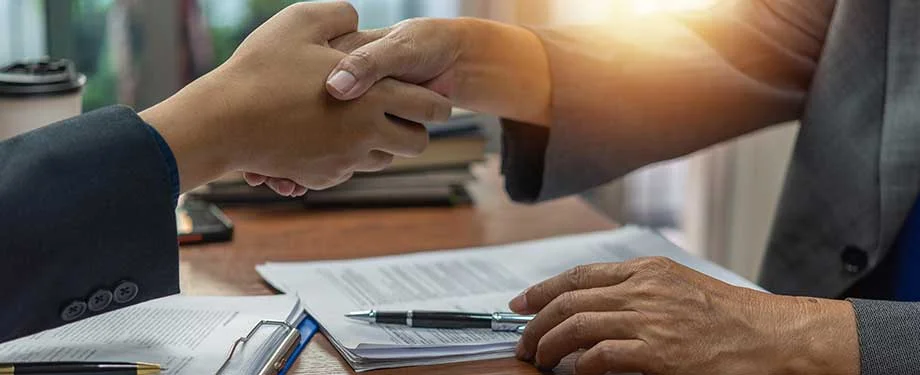 Quais s&atilde;o os tipos de seguro garantia de pagamento? Na imagem, empreendedores apertando a m&atilde;o representam os principais tipos de seguro garantia de pagamento: adiantamento e reten&ccedil;&atilde;o de pagamento 