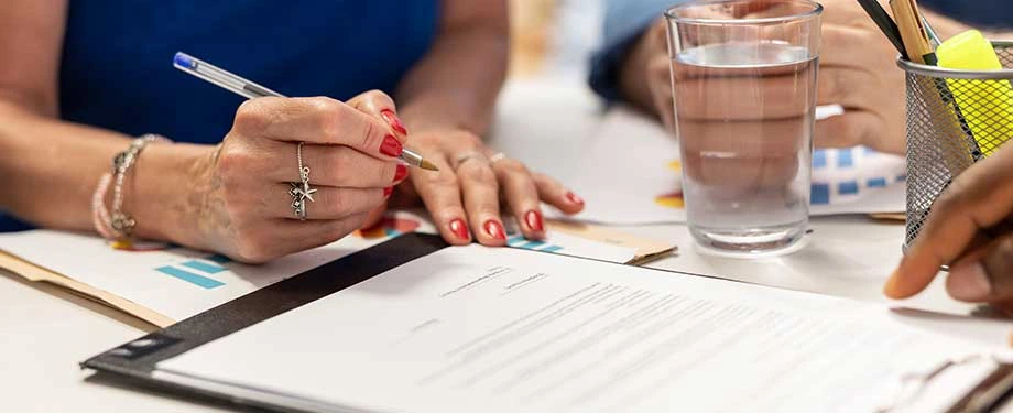 Quais são os tipos de seguros compreensivos? Na imagem, segurada assina apólice de seguro compreensivo, que garante diversos tipos de coberturas simultaneamente