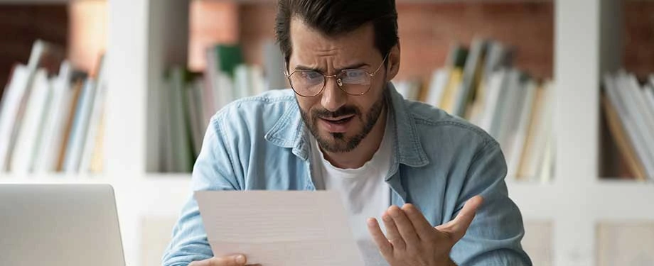 Qual a diferença entre erro formal e erro material no processo administrativo? Na imagem, homem demonstra indignação após perceber erro formal