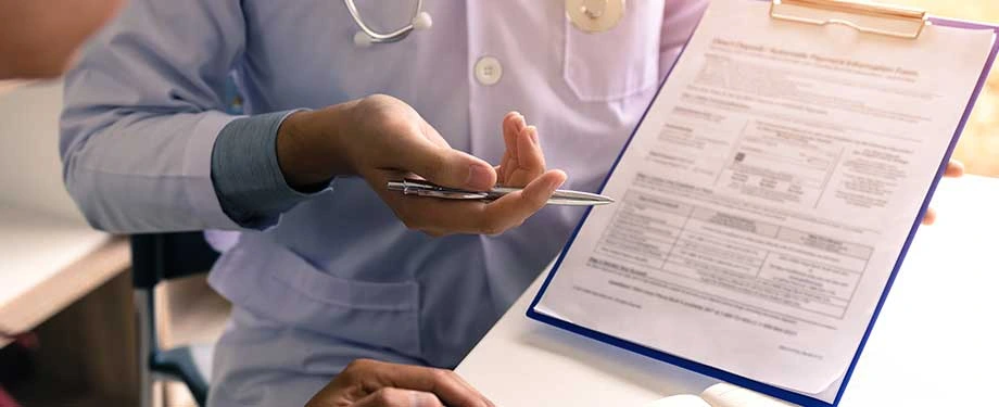 Quem deve preencher a Declaração Pessoal de Saúde? Na imagem, médico segurando formulário evidencia que beneficiário da apólice deve preencher a DPS