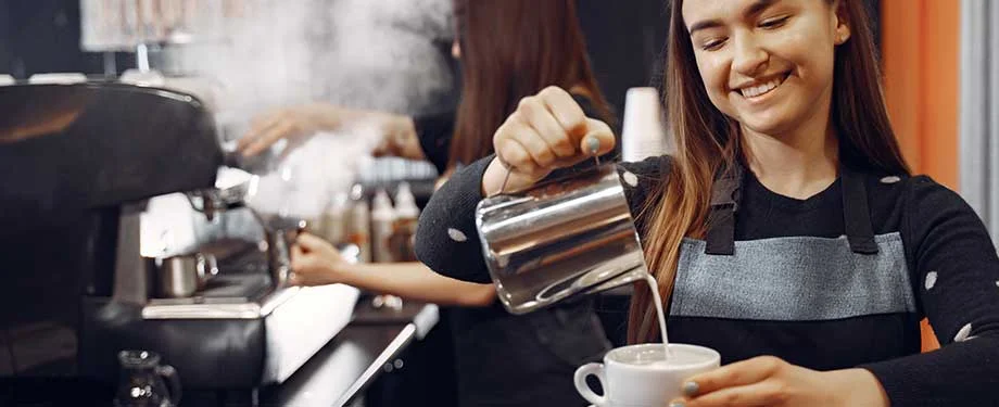 Qual a import&acirc;ncia de contratar o seguro cafeteria? Na imagem, funcion&aacute;rio fazendo bebida em alus&atilde;o ao seguro que protege a cafeteria contra danos patrimoniais e permite a continuidade do neg&oacute;cio 