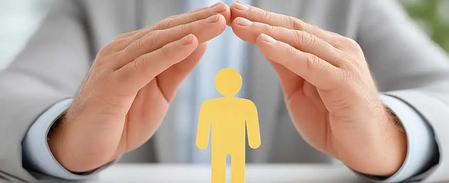 Qual a import&acirc;ncia do seguro de pessoas? Na imagem, m&atilde;os protegem boneco, evidenciando a import&acirc;ncia do seguro que garante tranquilidade financeira para o segurado e benefici&aacute;rios 