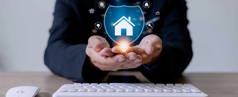Como funciona uma seguradora de casa? Na imagem, mãos com escudo evidenciam que as seguradoras residenciais oferecem coberturas para riscos como incêndio, roubos e danos elétricos