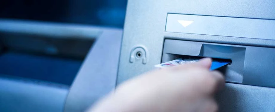 Qual &eacute; a import&acirc;ncia do seguro global bancos? Na imagem, pessoa inserindo cart&atilde;o no caixa eletr&ocirc;nico evidencia a necessidade de medidas que protejam o banco e os clientes 