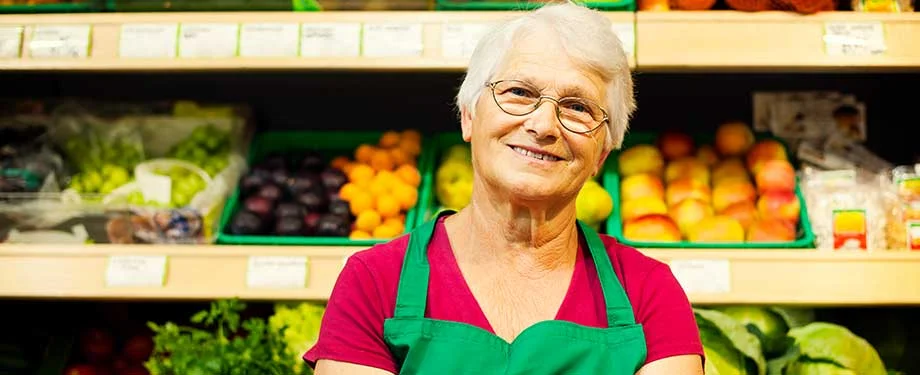 Qual é o melhor seguro para comércio? Na imagem, dona de supermercado sorrindo em alusão ao seguro supermercado, que garante a continuidade da operação em caso de imprevistos