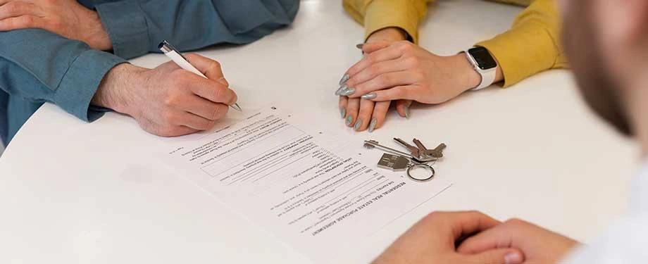 Qual o valor do seguro fiança para aluguel? Na imagem, casal assina contrato de aluguel de imóvel apresentando a apólice do seguro fiança aluguel