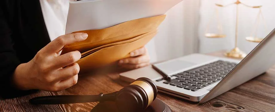 Quanto custa um seguro garantia judicial? Na imagem, advogado segura envelopes representando que o seguro garantia pode ser usado em processos judiciais, e os valores dependem de aspectos como tipo de processo e valor a ser garantido