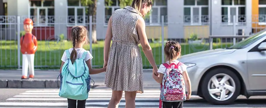 O seguro escolar é obrigatório? Na imagem, mãe leva crianças para escola em alusão ao seguro RC estabelecimento de ensino, que pode ser contratada por instituições de ensino 
