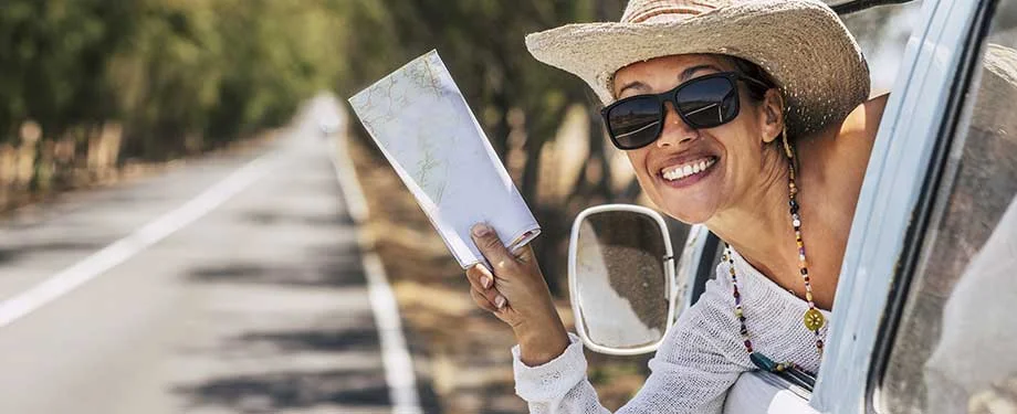 Quem pode contratar o seguro viagem excursão para empresas? Na imagem, mulher segurando mapa em alusão a importância do seguro viagem excursão para empresas, que pode ser contratado por qualquer tipo de empresa jurídica que realize atividades no ramo