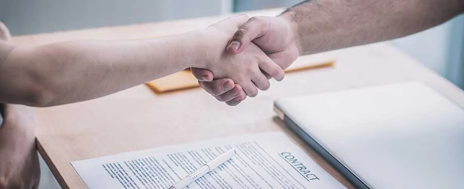 O que &eacute; garantia de pagamento? Na imagem, empreendedor aperta a m&atilde;o ap&oacute;s assinar contrato garantido por seguro garantia de pagamento 