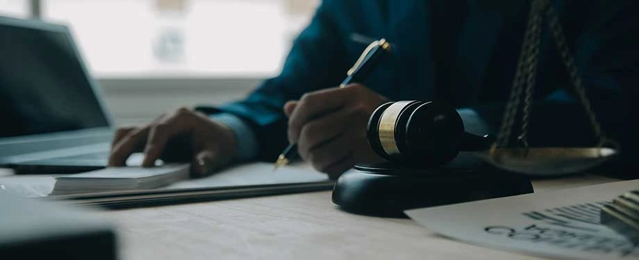 O que são pressupostos recursais penais? Na imagem, martelo da justiça e homem assinando documento em alusão à relação entre depósito recursal e seguro garantia